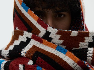 Person with curly hair wearing a thick scarf around her head