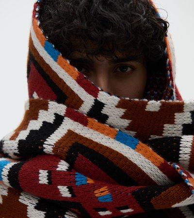 Person with curly hair wearing a thick scarf around her head