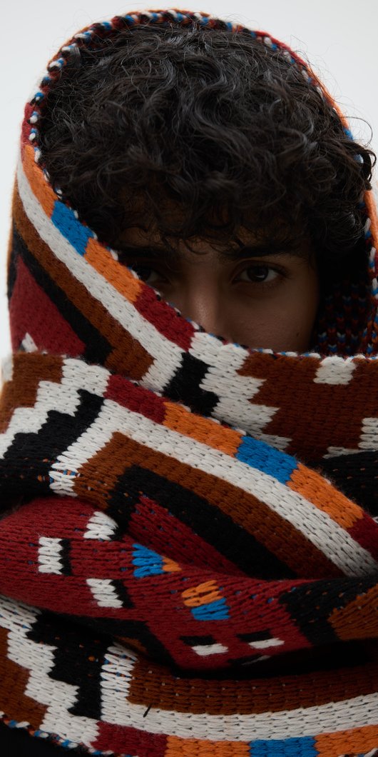 Person with curly hair wearing a thick scarf around her head