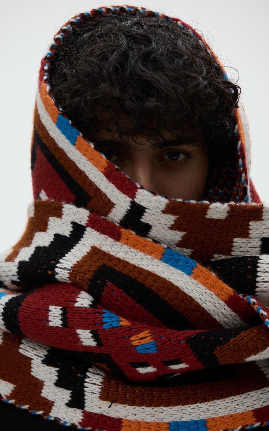 Person with curly hair wearing a thick scarf around her head