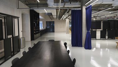 Room with long tables and chair divided by a curtain