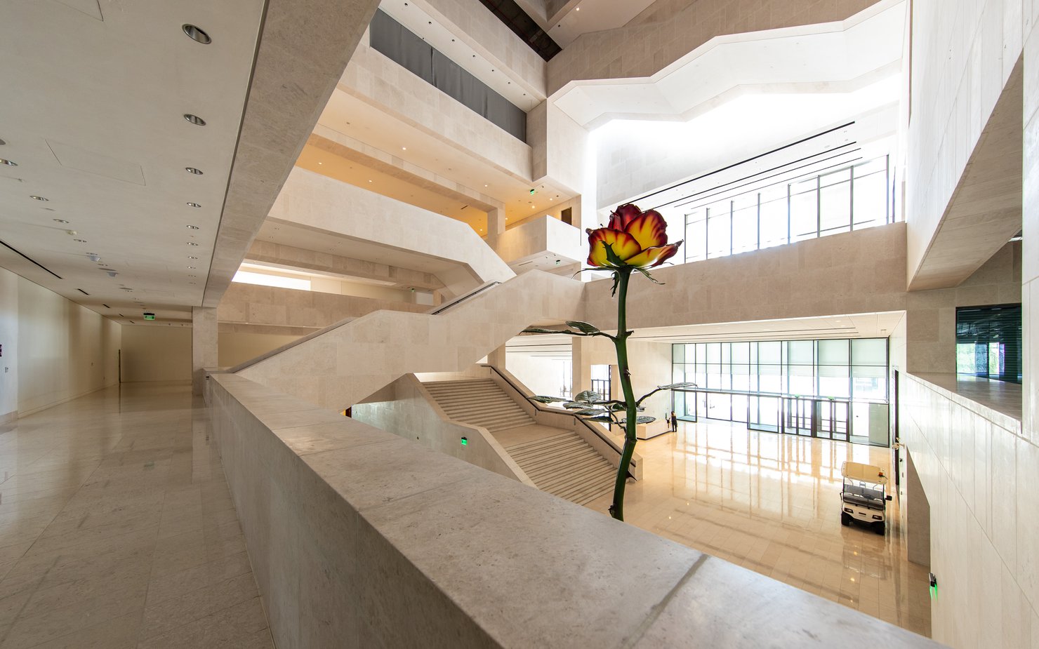 A two-story tall metal sculpture of a rose with red and white petals inside the entrance to the M7 building.