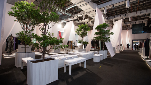 Space with black carpet, seating area and booths with clothing