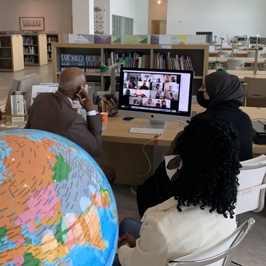 A man and a woman sitting in front of a computer inside MIA hosting a Planet Kids event on Zoom