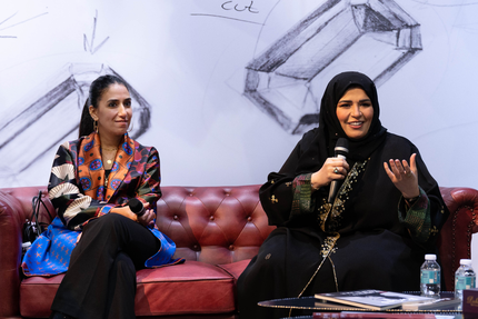 Two women on a couch speaking to the audience