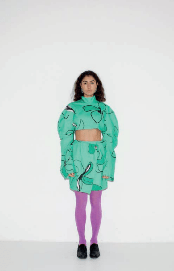 Model standing in a sweater top and skirt