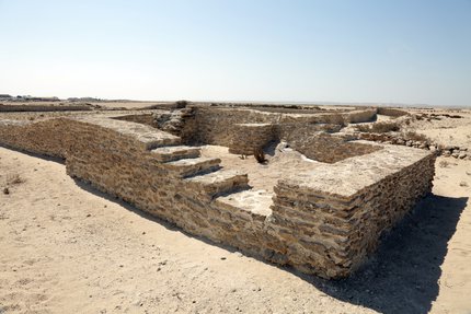 A stone structure on a beach with a visible set of stairs.