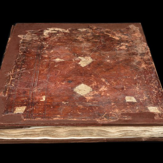 A photo showing the cover of the Al Zubarah Qur'an, bound with leather and covered in intricate designs which have weathered with time
