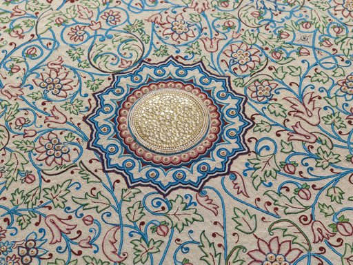 An embroidered floral shape made up of diamonds placed on a gold and silver ground.