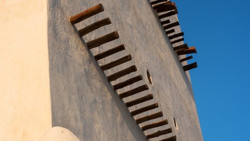A close-up view of Barzan tower showing its white walls and protruding wooden shafts
