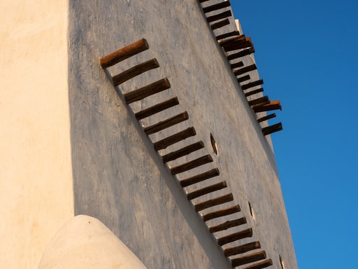 A close-up view of Barzan tower showing its white walls and protruding wooden shafts