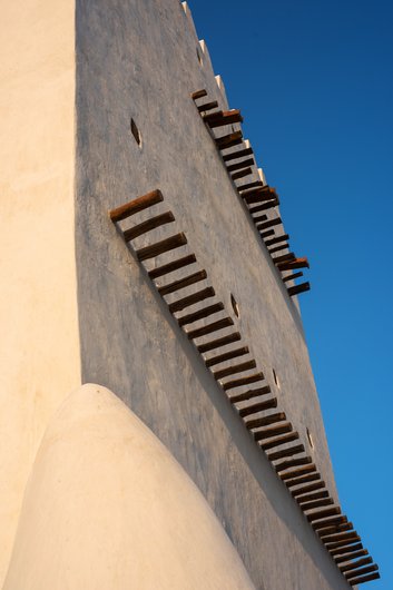 A close-up view of Barzan tower showing its white walls and protruding wooden shafts