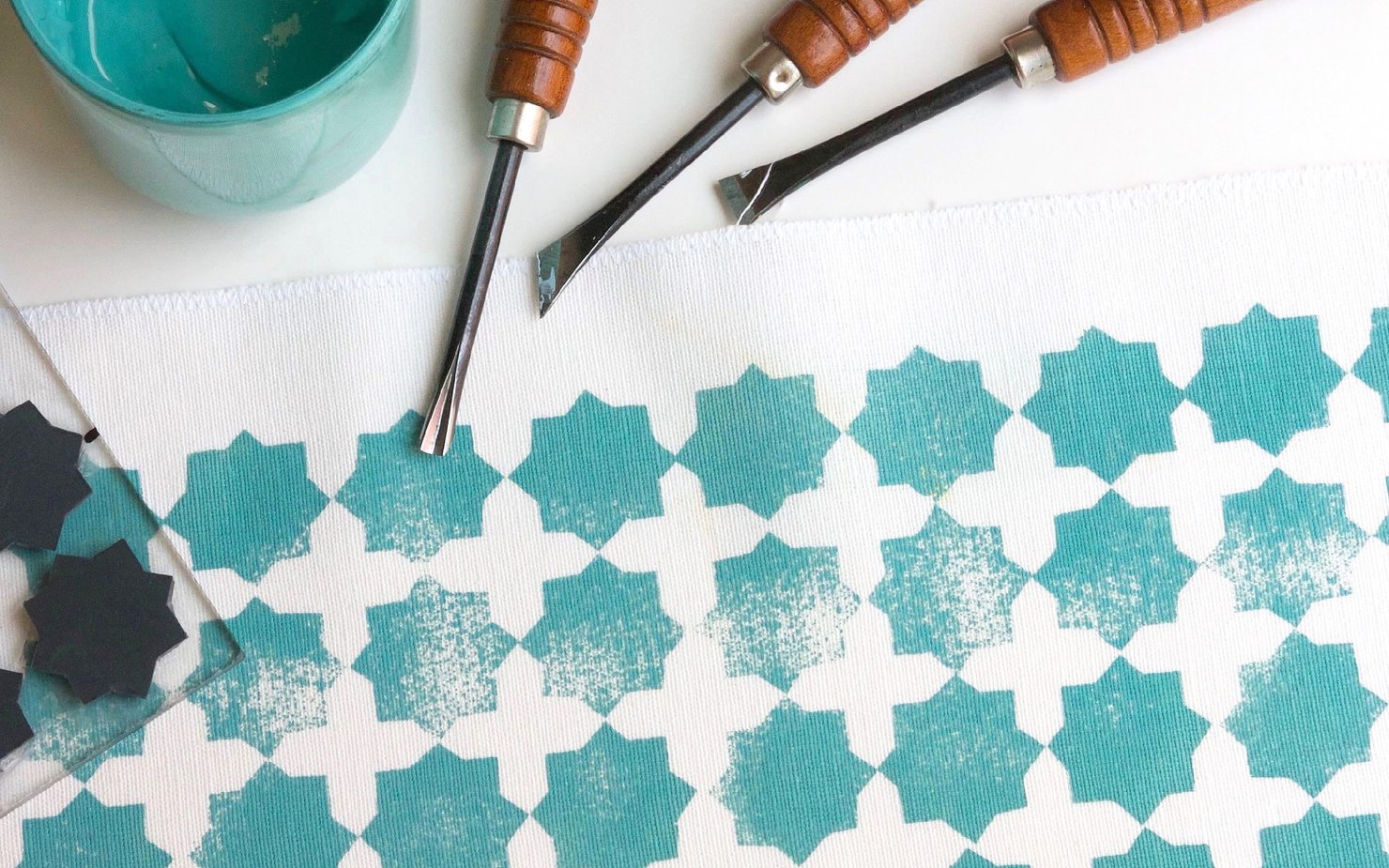 Blue paint, wooden stamps and tools laid over a block printed canvas