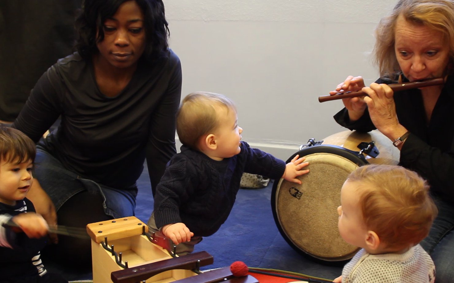 Three babies enjoying playing music with some instructors