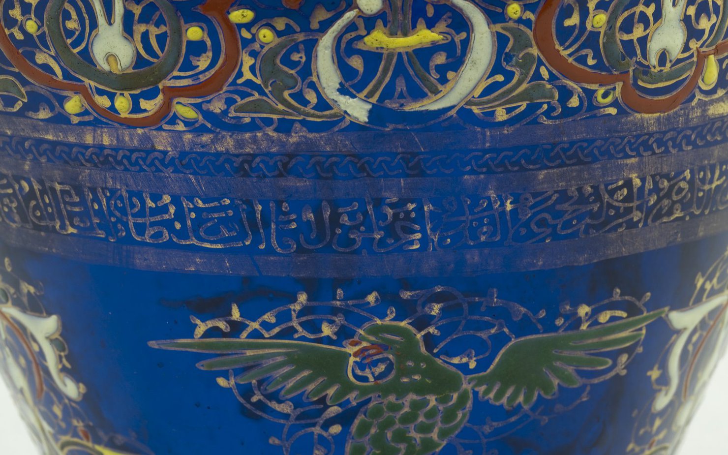 Details of a blue ceramic pot painted with gold Arabic letters and Islamic designs