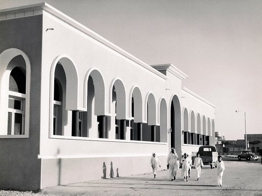 مبنى دار الكتب بالأبيض والأسود ويظهر أمامها رجل وعدة أطفال قطريون