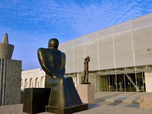 Exterior view of Mathaf: Arab Museum of Modern Art building with a group of three large sculptures positioned in front of it