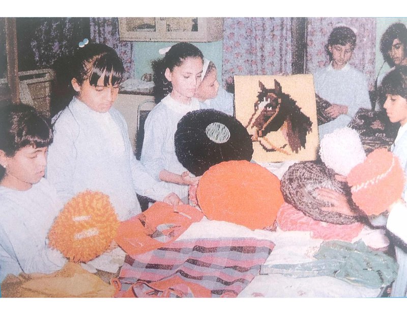 Old picture of female students in a knitting class wearing a school uniform.