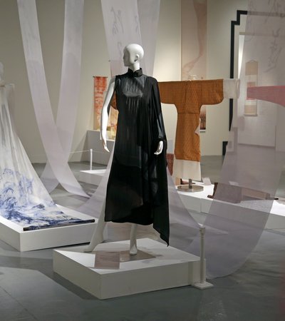 A shot of mannequins in colourful artistic dresses with additional  printed fabrics hanging in the background