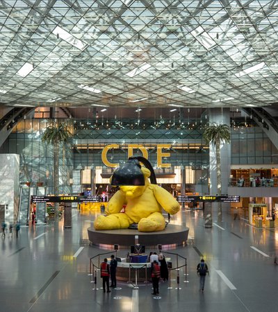 A sculpture of a yellow teddy with a lamp above its head at Hamad International Airport