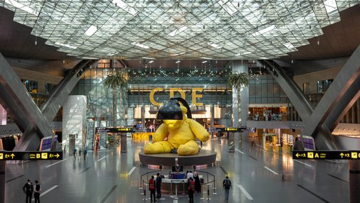 A sculpture of a yellow teddy with a lamp above its head at Hamad International Airport