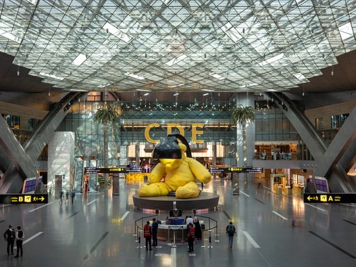 A sculpture of a yellow teddy with a lamp above its head at Hamad International Airport