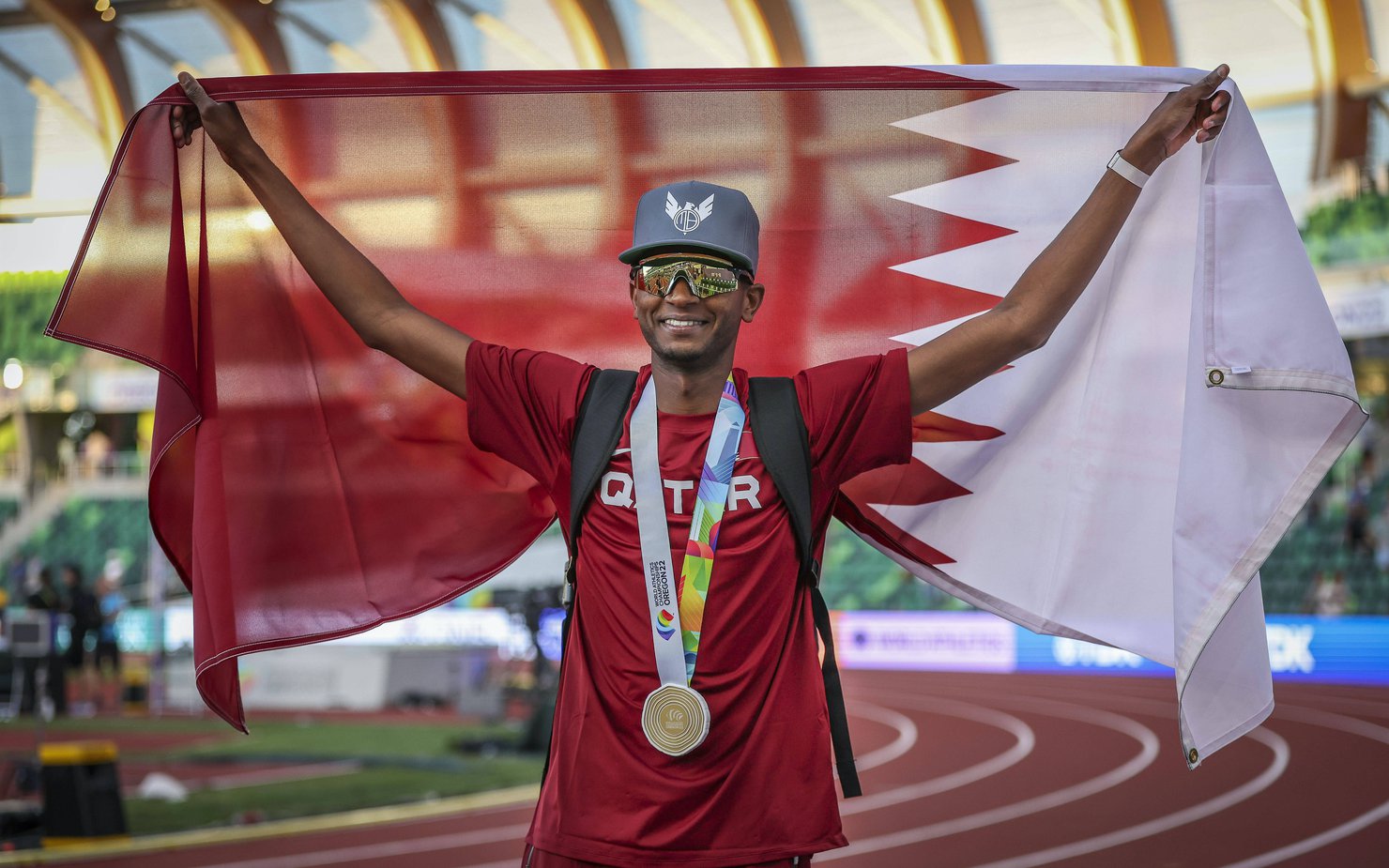 Athlete Mutaz Essa Barshim holding a Qatari flag after a victory
