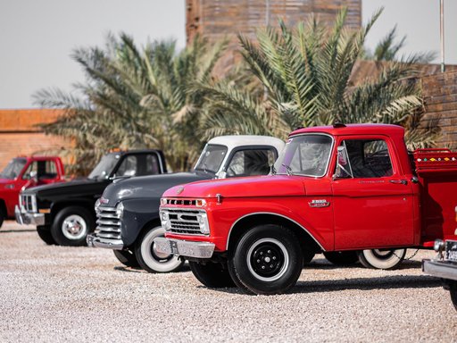 A row of classic cars parked in bright daylight for the Mal Lawal exhibition