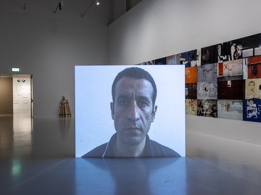A projection of the artist, Taysir Batniji's face, in the middle of a gallery space.