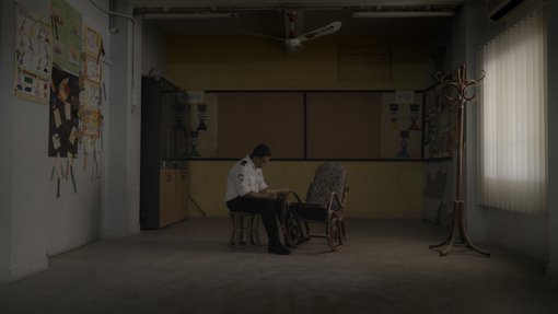 Picture of a security guard sitting next to an empty chair