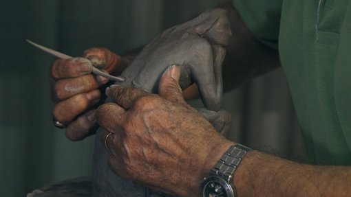 Image of an artist sculpting a miniature sculpture of a woman