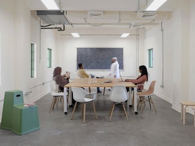 A small meeting room, with a central table and chairs with several people.