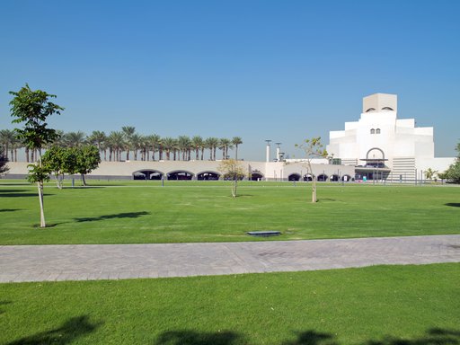 An open parkland space with green grass and native trees and the Museum of Islamic Art in the background