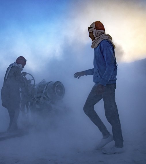 Two men stand in a dust filled landscape.