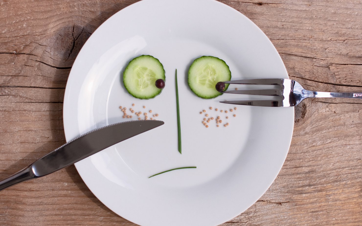 A sad face created by vegetables, sitting on top of a white plate