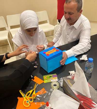 Three individuals gathered around a table engaging in an arts and crafts activity box