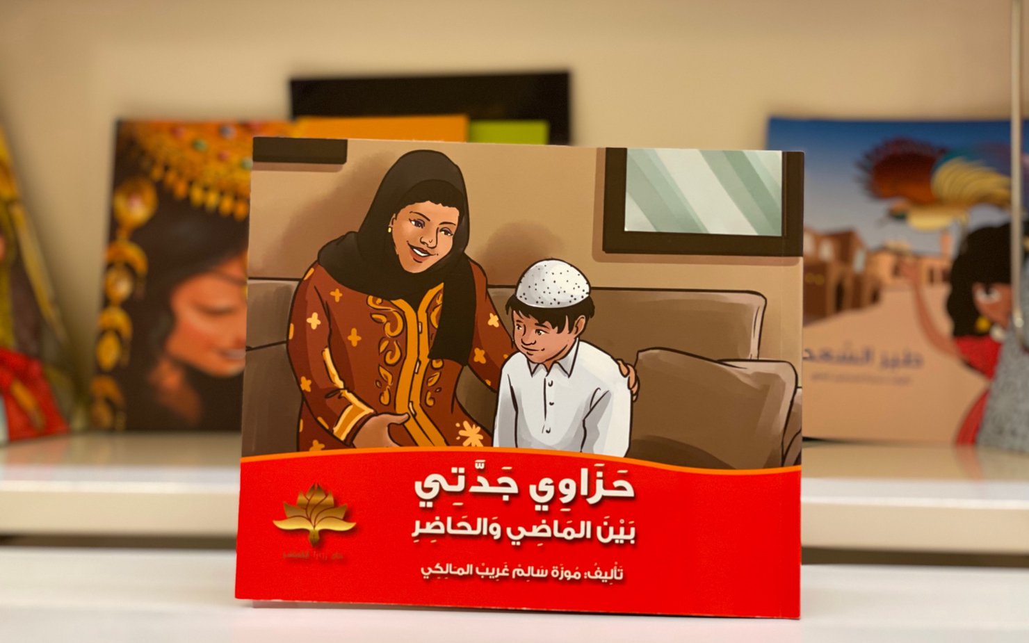 A children's book cover with an illustration of a Qatari grandmother and her grandson both dressed in traditional attire