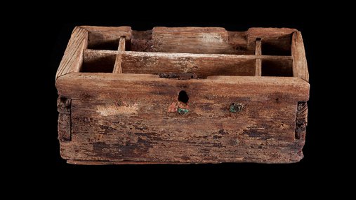The exterior of a pearl box, made of wood, against a black background