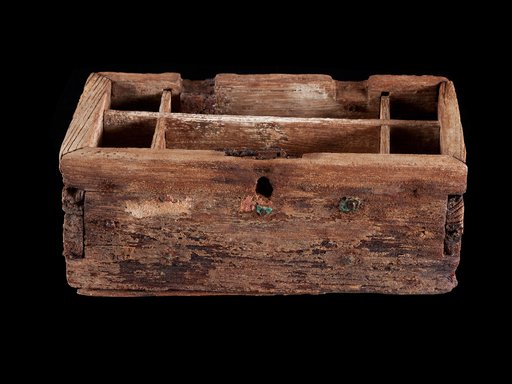 The exterior of a pearl box, made of wood, against a black background