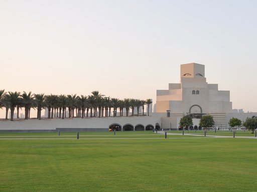 Large open parkland with native trees and lush green grass and the Museum of Islamic Art in the background