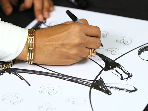 A woman sketches with a black pen on a large piece of white paper