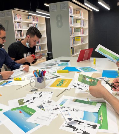 Four young men sit around a table with paper clippings of different sports.
