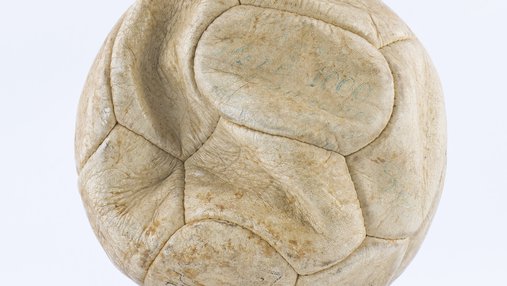 A white football, time-weathered leather, with faint blue writing visible.