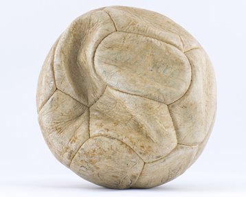 A white football, time-weathered leather, with faint blue writing visible.