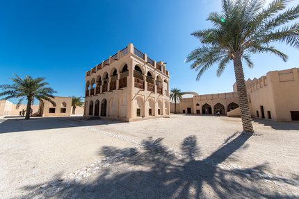 Restored historic palace with arches and sand coloured buildings in the background