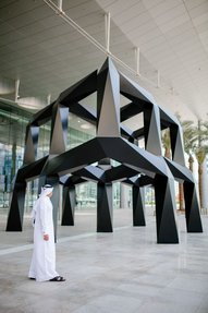 A man in traditional Qatari attire looking up at Tony Smoths lifesize art piece, Smoke
